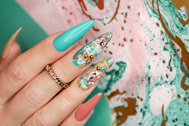 Manicura de color creativa con pedrería en uñas largas.