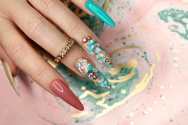 Manicura de color creativa con pedrería en uñas largas.