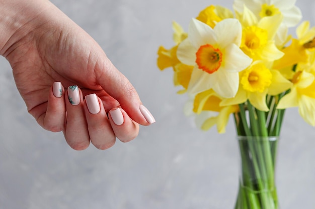 Manicura desnuda de primavera o verano con adornos florales contra flores borrosas Moda y belleza