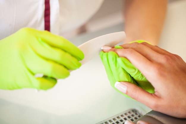 Manicura. Experta maestra de manicura sosteniendo el archivo en sus manos mientras trabajaba en su salón de belleza