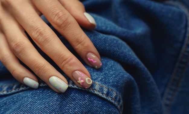 Manicura femenina hermosa del verano en el fondo del dril de algodón