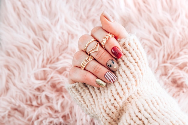 Manicura femenina de Navidad. Diseño de arte de uñas con temática de año nuevo sobre fondo de piel rosa