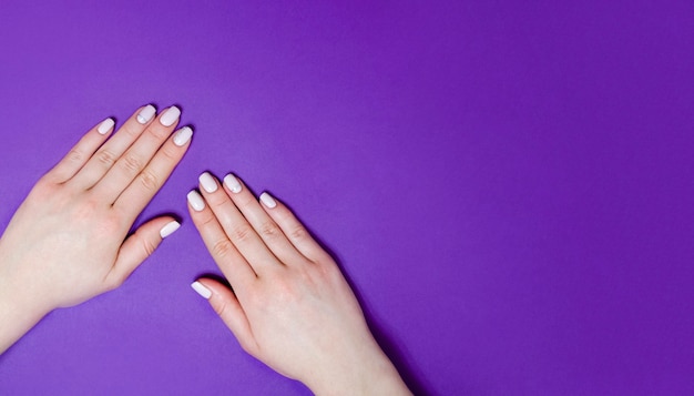 Manicura femenina sobre un fondo brillante. Fondo morado. Bandera.