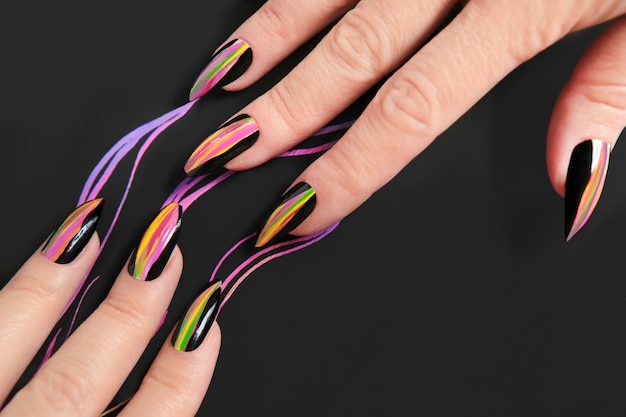 Manicura en forma afilada de uñas con líneas multicolores.