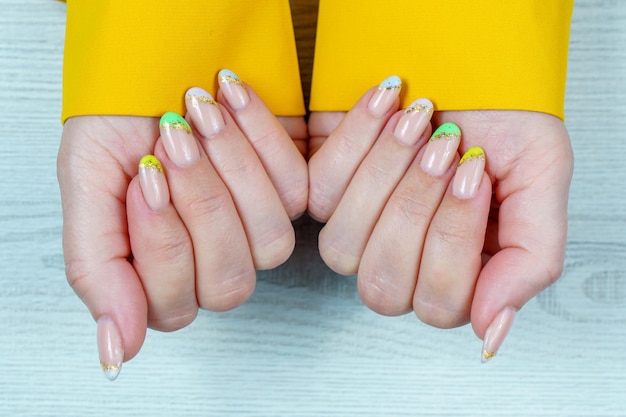 Manicura francesa en verde amarillo violeta sobre un fondo sólido Arte de uñas en uñas de mujer Mujer