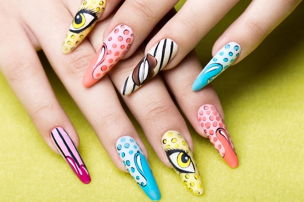 Manicura hermosa larga en estilo pop-art en dedos femeninos. Diseño de uñas. De cerca.