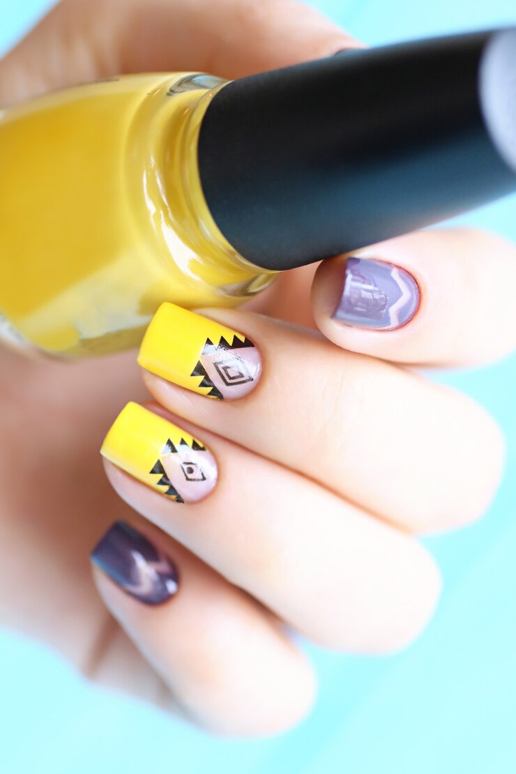 Foto manicura de mujer de color amarillo y púrpura brillante con arte nulo. ornamento étnico negro. diseño transparente. uñas brillantes.