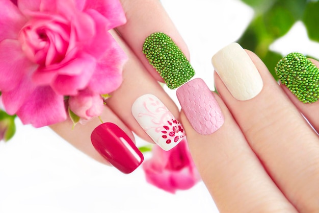 Manicura multicolor en uñas cortas con flor.