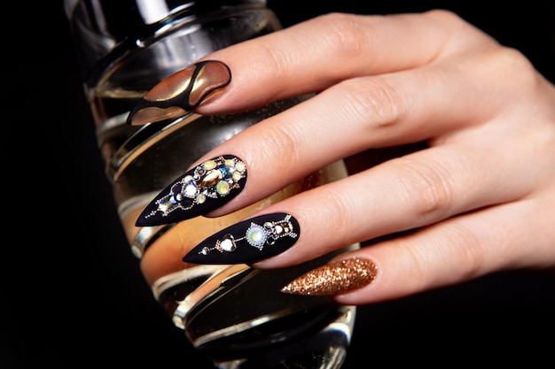 Manicura negra y dorada con diamantes.