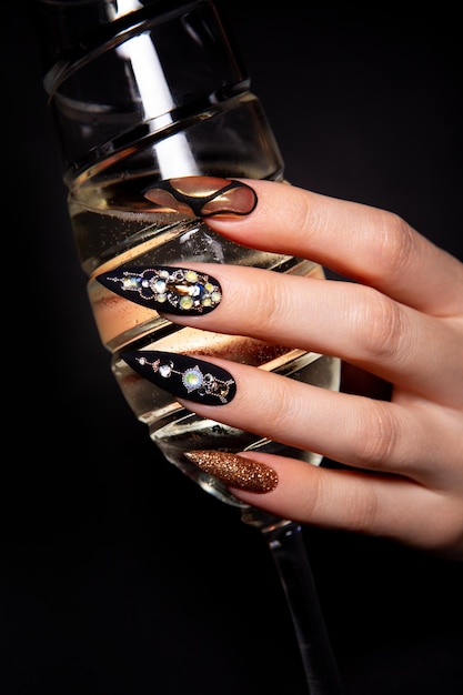 Manicura negra y dorada con diamantes.