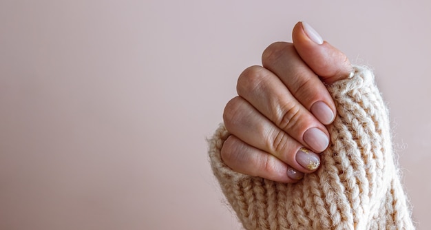 Manicura pastel femenina de moda con estilo. Manos femeninas sobre fondo beige.