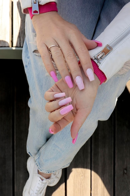 Foto manicura rosa con uñas largas con anillo.