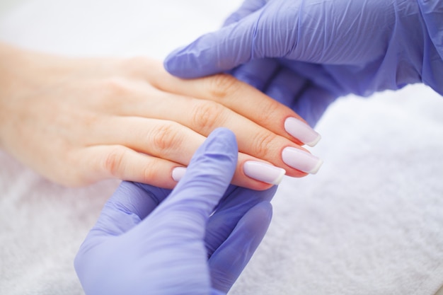 Foto manicura spa. manicura francesa en el salón de spa. manos de mujer en un salón de manicura recibiendo un procedimiento de manicura. procedimiento de manicura