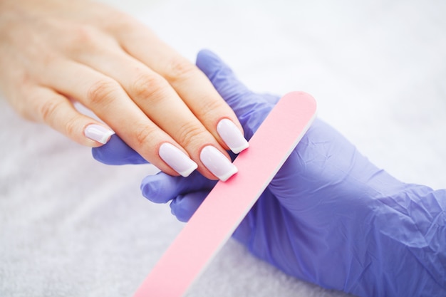 Manicura SPA. Mujer en un salón de uñas recibiendo una manicura por una esteticista