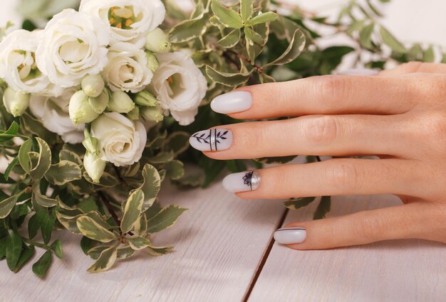 Manicura suave y ordenada en manos femeninas sobre un fondo de flores. Diseño de uñas