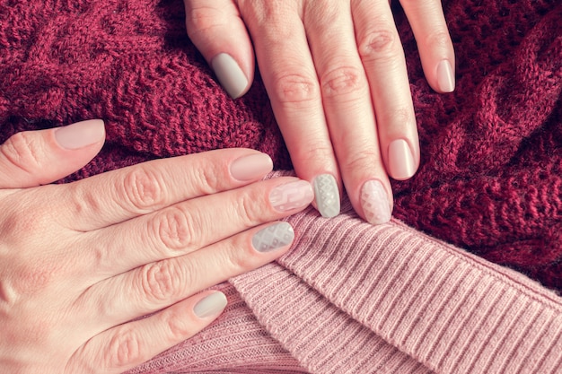 Manicura de textura tejida en uñas de colores rosa y gris.