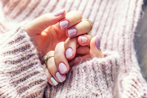 Manicura de uñas de arte para novia en suéter morado. Uñas de gel en color rosa suave.