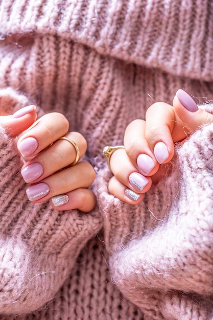 Manicura de uñas de arte para novia en suéter morado. Uñas de gel en color rosa suave.