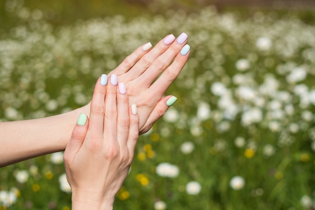 Manicura de verano en uñas cortas. Manos femeninas en prados. Gel Polish.