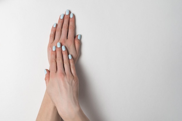 Manicure azul de verão em unhas curtas Mãos em um fundo branco Copie o espaço