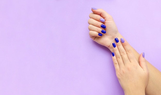 Manicure azul e lilás nas mãos da mulher