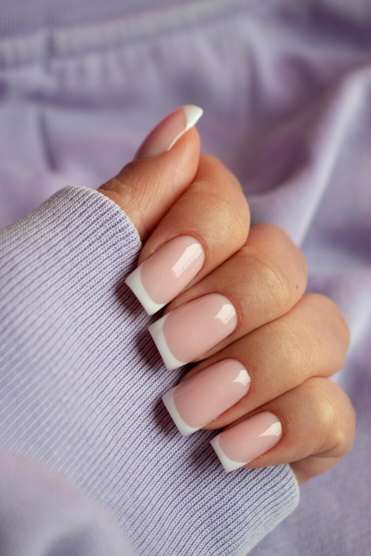 Foto manicure clássica francesa dedos femininos com lindas unhas em fundo lavanda closeup foco seletivo conceito de spa cuidados com a pele tratamentos de beleza salão de beleza e mulher bonita