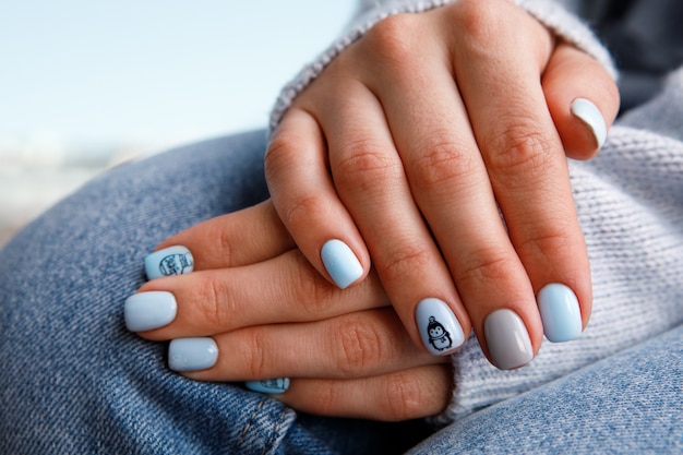 Manicure delicada em tons pastel para uma garota em um fundo de roupas