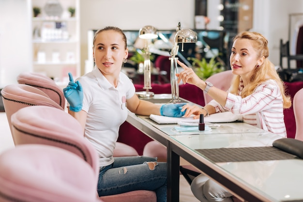 Manicure duvidosa virando-se e mulher apontando com o dedo