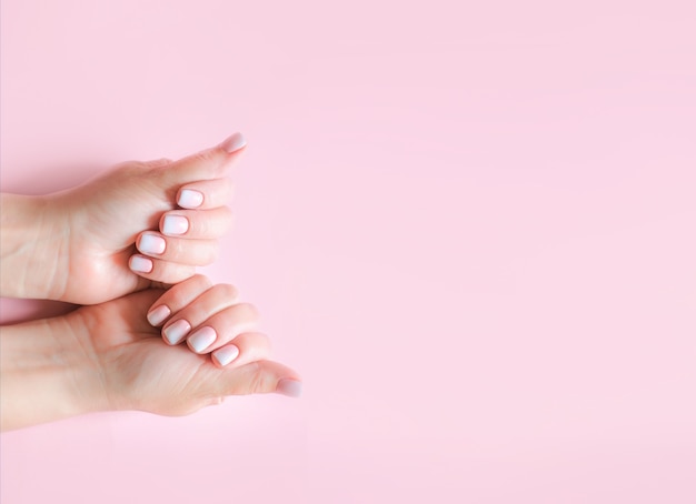 Manicure e mãos em gradiente spa close da mão da mulher bonita unhas bem cuidadas e pele das mãos macias unhas bonitas da mulher com fundo rosa lindo da manicure baby boomer