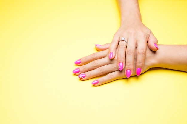 Manicure elegante rosa sobre fundo amarelo