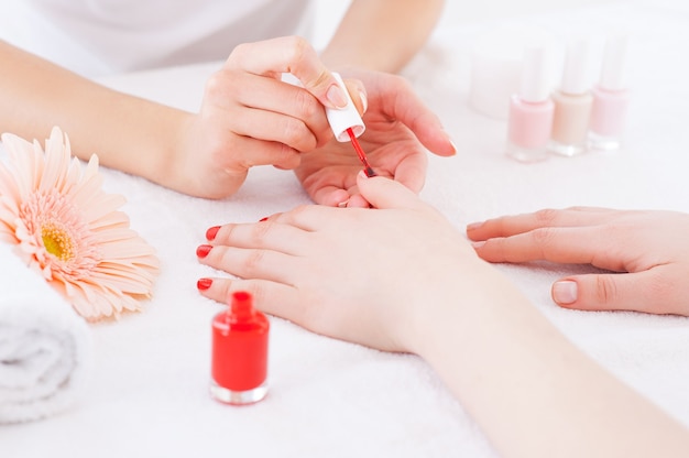 Manicure em ação. Close de manicure fazendo manicure vermelha em uma cliente