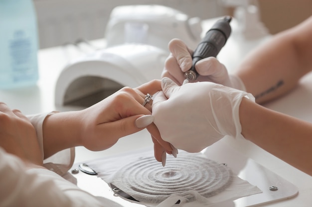 Manicure fazendo uma manicure no salão. Mestre atendendo seu cliente. Procedimento de cuidados com as unhas.