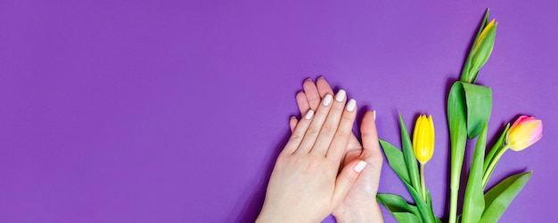 Manicure feminina em um fundo brilhante. Fundo roxo com flores. Bandeira.