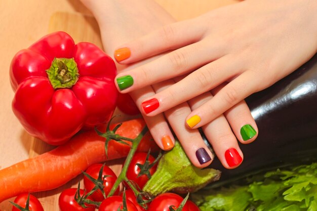 Manicure infantil com design de verniz colorido para as unhas na menina com pepino, tomate, cenoura, berinjela de alimentos diferentes.