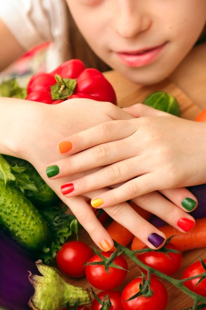 Manicure infantil com design de verniz colorido para as unhas na menina com pepino, tomate, cenoura, berinjela de alimentos diferentes.