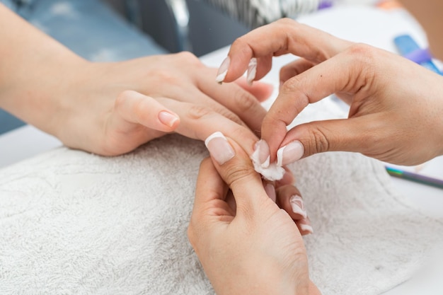 Manicure Latina realizando uma limpeza de unhas adequada com um cotonete