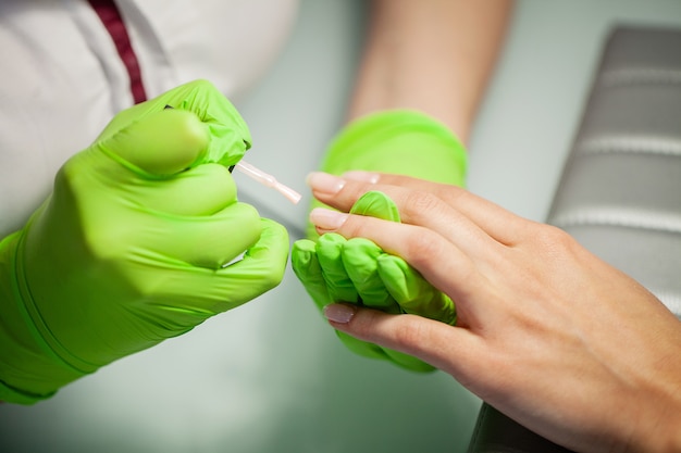 Manicure. Mestre hábil de manicure segurando o arquivo nas mãos enquanto trabalhava em seu salão de beleza