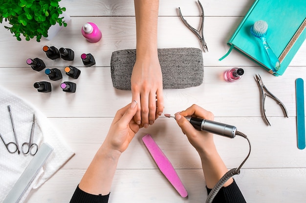 Foto manicure para a cliente. close das mãos de uma manicure e cliente em um fundo de madeira