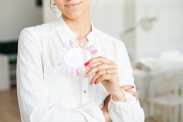 Manicure pedicure mestre segurando paleta de cores de unhas em cores neutras naturais