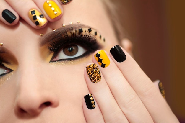 Manicure preto e amarelo com strass e maquiagem