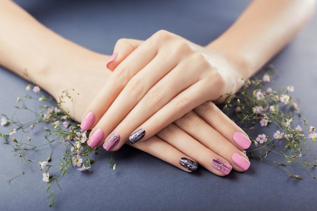 Manicure rosa e preto com flores em nail art de fundo cinza