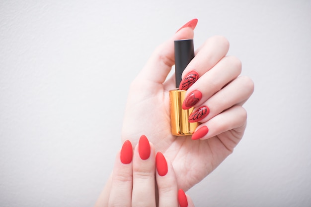 Manicure vermelho com um padrão. frasco com esmalte