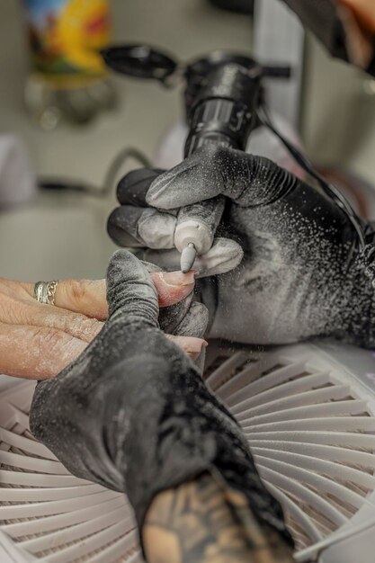 Manicurista a consertar as unhas de um cliente.