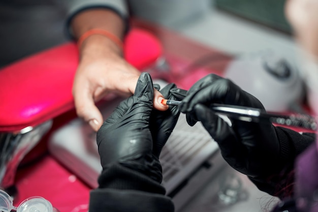 Manicurista aplica esmalte de uñas en las uñas masculinas en un spa o salón de manicura