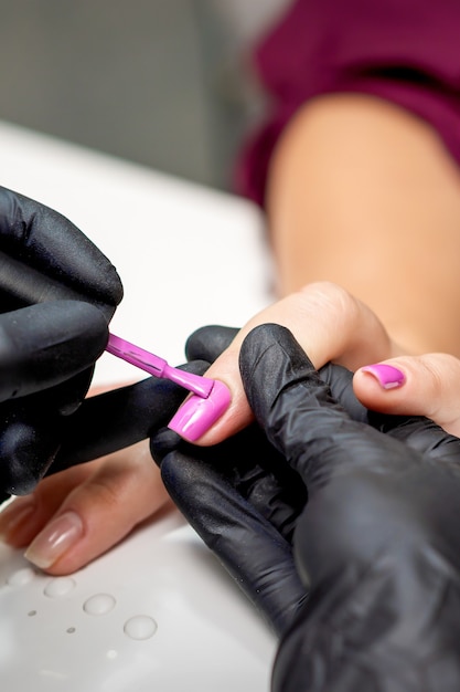 Manicurista aplicando esmalte de uñas rosa