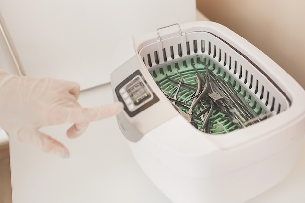 La manicurista esteriliza sus herramientas en el autoclave o en el horno. Domina el salón preparando sus instrumentos para la desinfección.