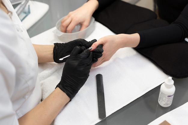 Manicurista femenina que limpia la cutícula con una herramienta profesional de empuje de manicura