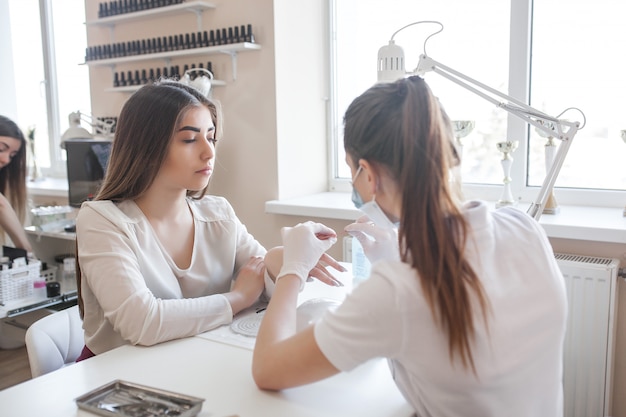 Manicurista haciendo una manicura en el salón. Amo sirviendo a su cliente. Procedimiento de cuidado de uñas.