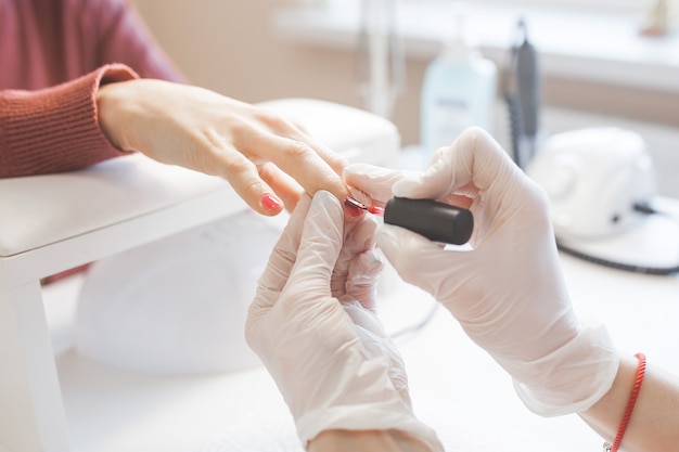 Manicurista haciendo una manicura en el salón. Amo sirviendo a su cliente. Procedimiento de cuidado de uñas.