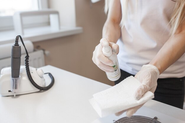 Manicurista limpiando su lugar para atender a un nuevo cliente. Mesa de salón esterilizante para prevenir infecciones.